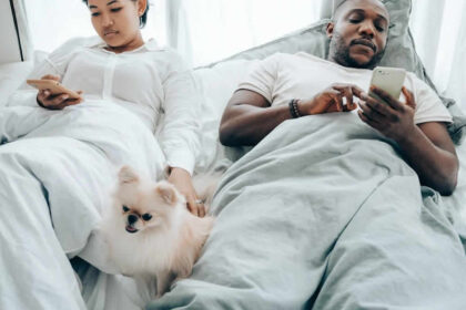 casal homem e mulher e cachorro na cama